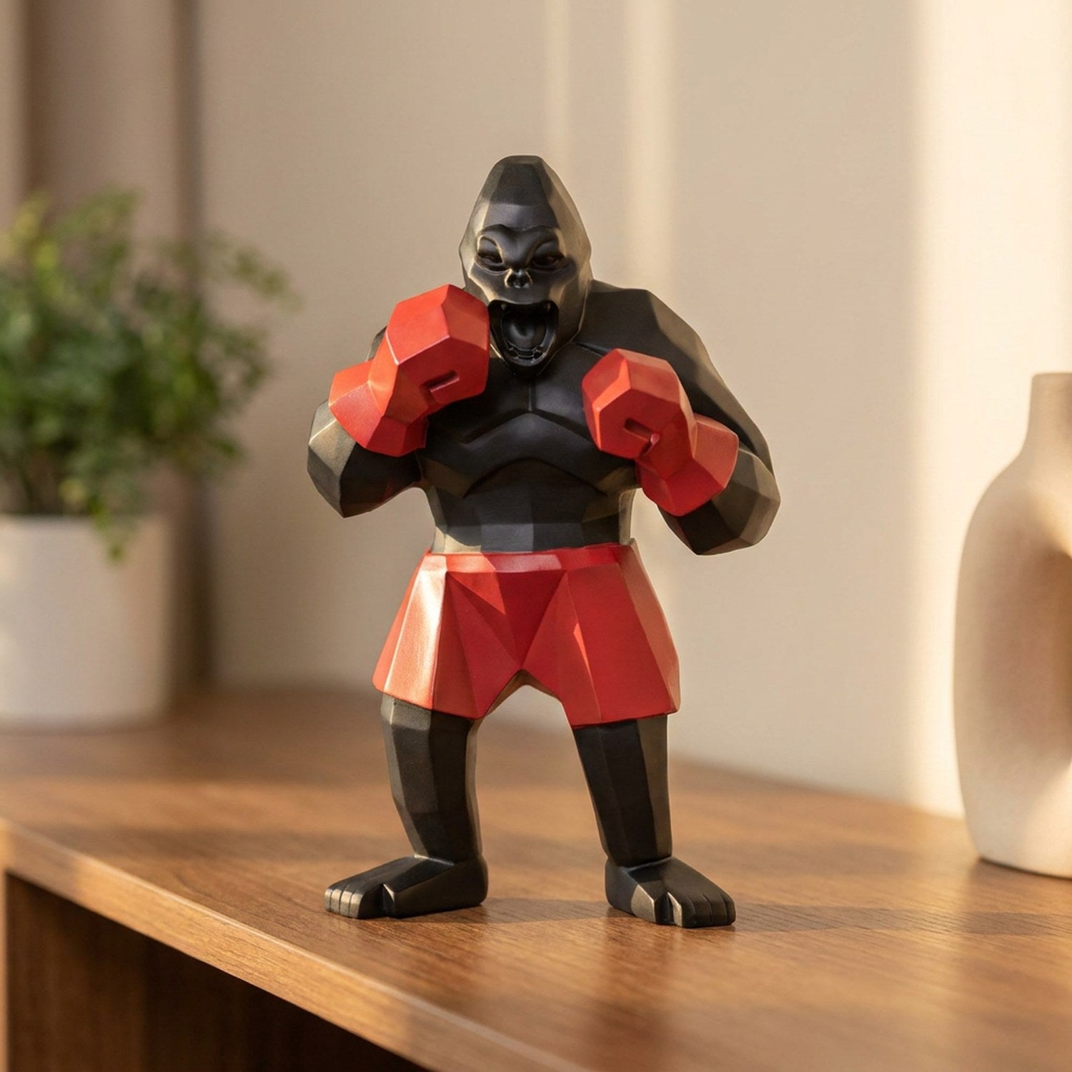 Statue de gorille boxeur noir en résine aux gants rouges posée sur une étagère déco moderne
