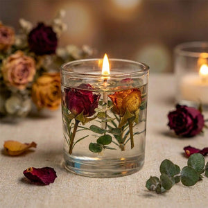 Bougie parfumée aux roses séchées dans un verre transparent allumée sur une nappe en lin avec fleurs séchées