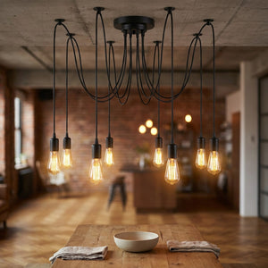 Lustre araignée industriel vintage 8 têtes métal noir mat suspendu dans un loft industriel avec ampoules Edison allumées au-dessus d'une table en bois