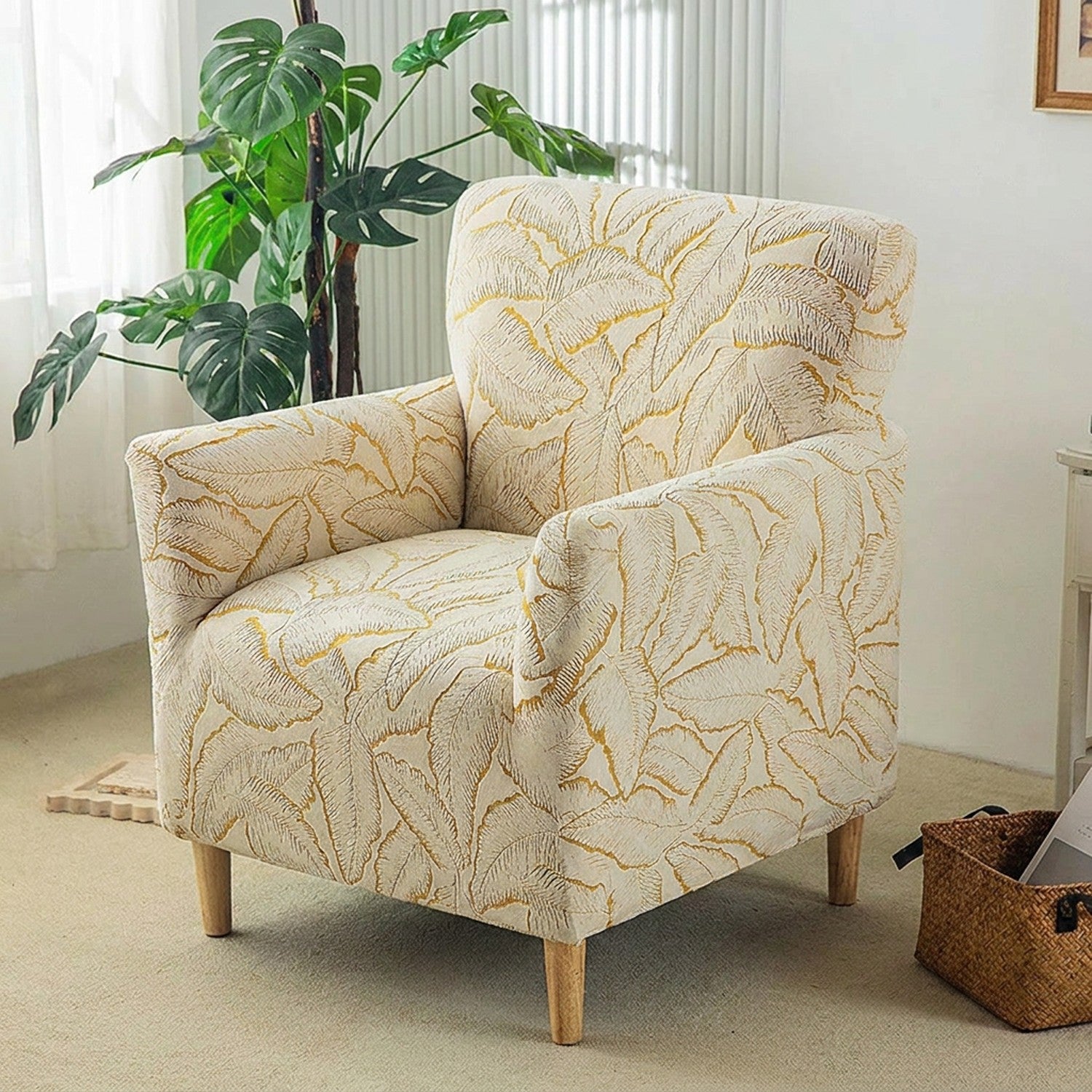 Housse de fauteuil club en jacquard à motif de feuilles dorées installée sur un fauteuil dans un salon lumineux
