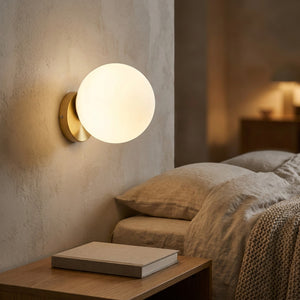 Applique murale boule de verre dorée diffusant une lumière chaude dans une chambre