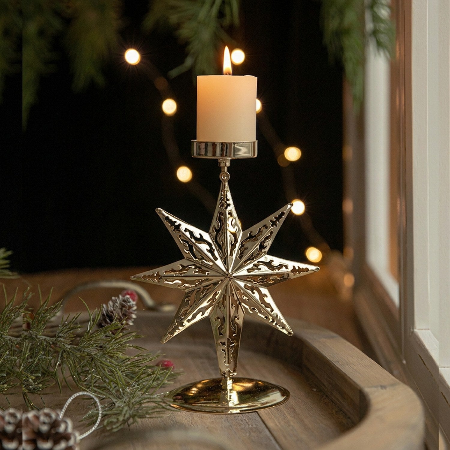 Chandelier de Noël en métal doré à motif étoile avec bougie allumée sur un plateau en bois