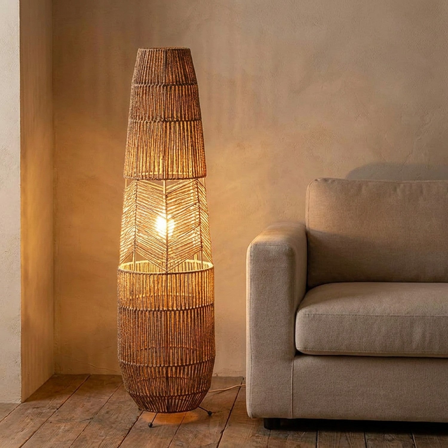 Lampadaire en rotin tressé allumé d'une lumière chaude posé dans un salon cosy près d'un canapé beige