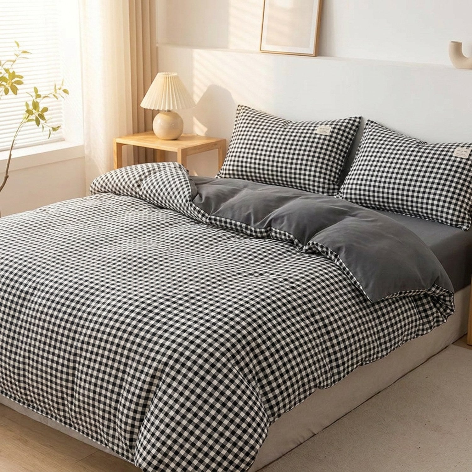 Housse de couette à carreaux vichy noirs posée sur un lit fait dans une chambre lumineuse et chaleureuse