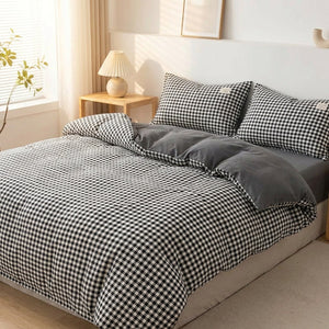 Housse de couette à carreaux vichy noirs posée sur un lit fait dans une chambre lumineuse et chaleureuse