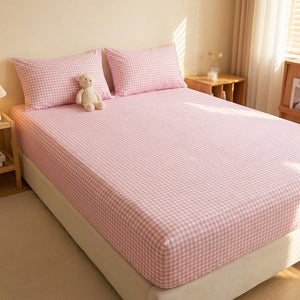 Drap-housse à carreaux rose installé sur un lit fait dans une chambre chaleureuse