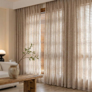 Rideau translucide beige en tissu aspect lin suspendu à une grande fenêtre dans un salon chaleureux