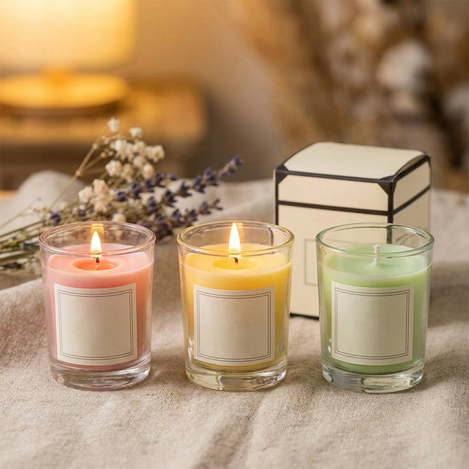Bougies parfumées colorées en cire de soja allumées près de leur coffret cadeau dans une ambiance cosy