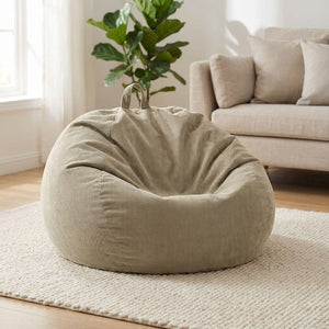 Housse de pouf poire en velours côtelé beige posée au sol dans un salon lumineux