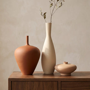 Ensemble de trois vases en céramique mate terracotta et beige style nordique sur un meuble en bois