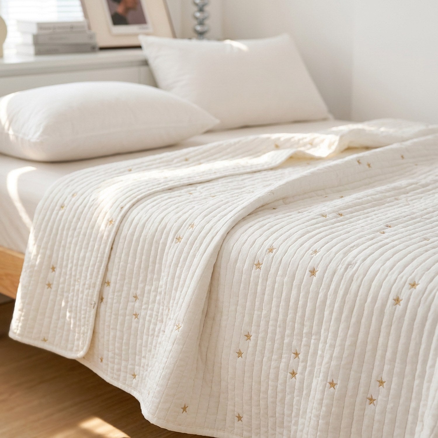 Couvre-lit matelassé blanc brodé d'étoiles dorées posé sur un lit avec coussins