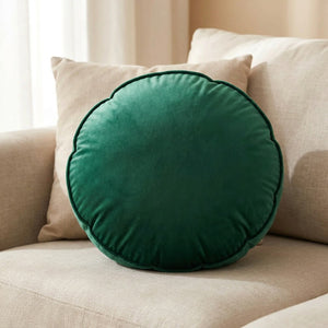 Housse de coussin ronde en velours vert émeraude posée sur un canapé clair lumineux