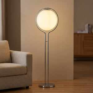 Lampadaire boule blanche opaline sur structure chromée dans un salon chaleureux