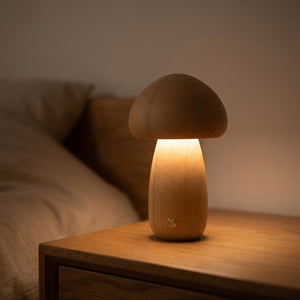 Lampe de chevet champignon en bois clair allumée posée sur une table de nuit