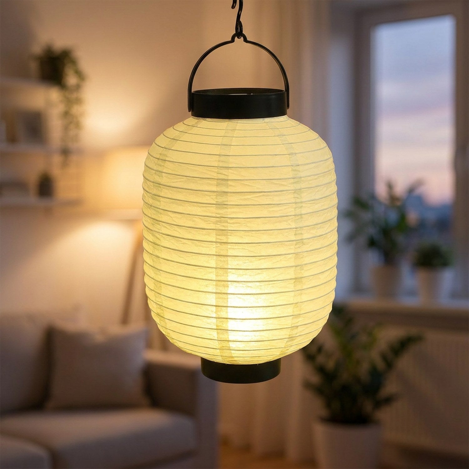 Lanterne japonaise en papier blanc crème suspendue et allumée diffusant une lumière LED chaude sous une terrasse en bois