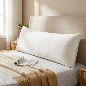 Housse de coussin lombaire en velours blanc posée sur un lit dans une chambre lumineuse