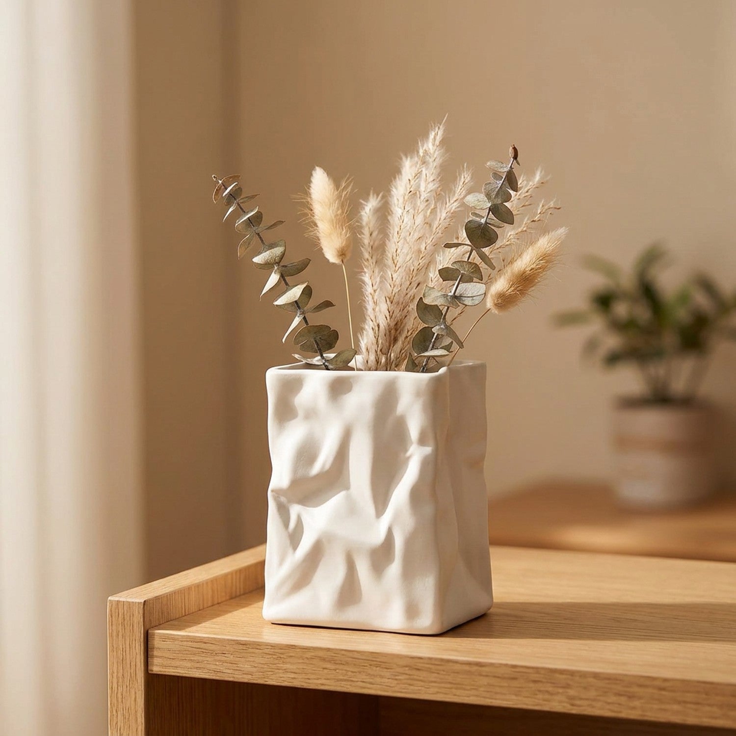 Vase en résine froissée style sac en papier blanc posé sur une étagère en bois avec eucalyptus