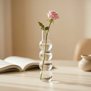 Vase en verre à bulles transparent avec une rose posé sur une table lumineuse