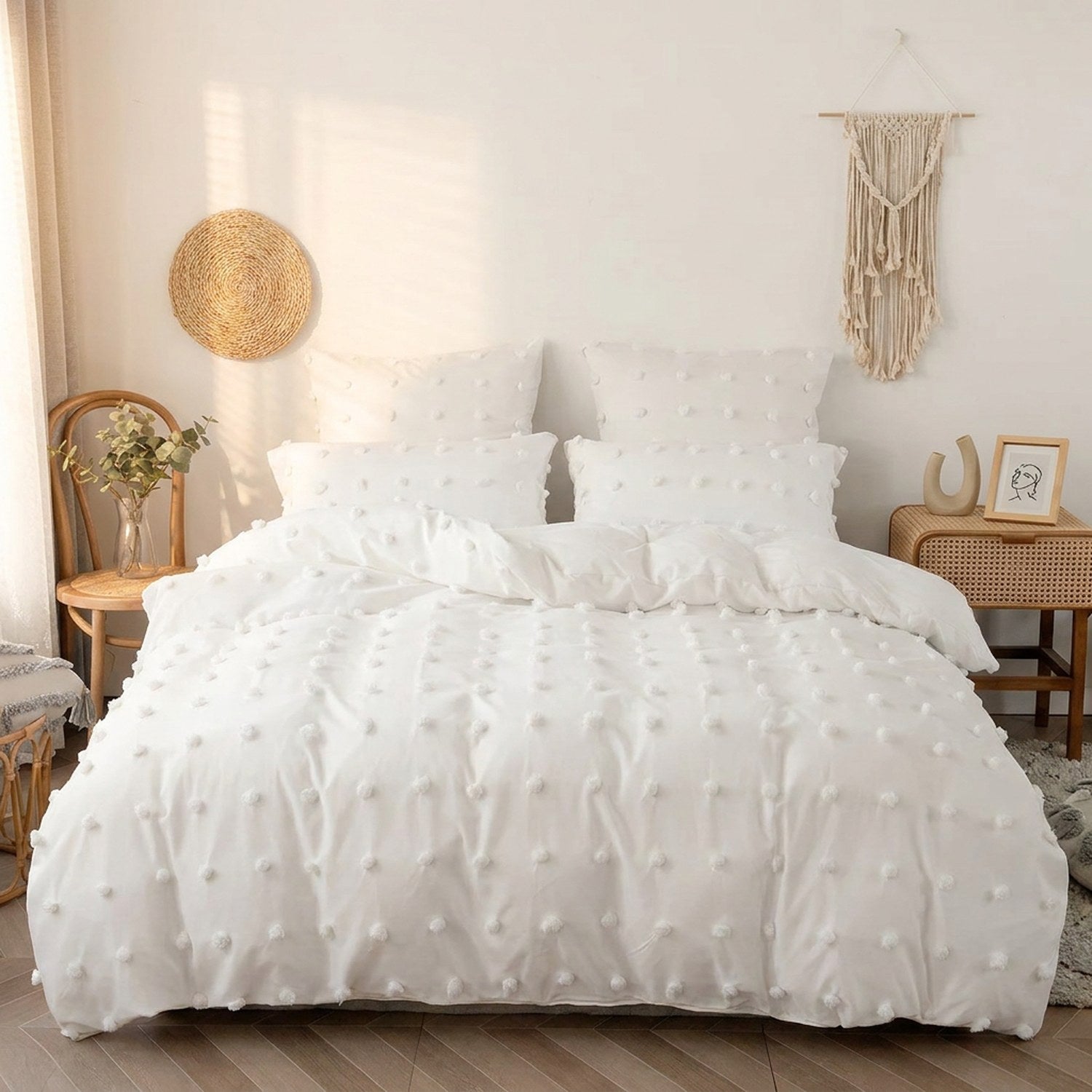 Parure de lit blanche à pompons installée sur un lit dans une chambre bohème chaleureuse