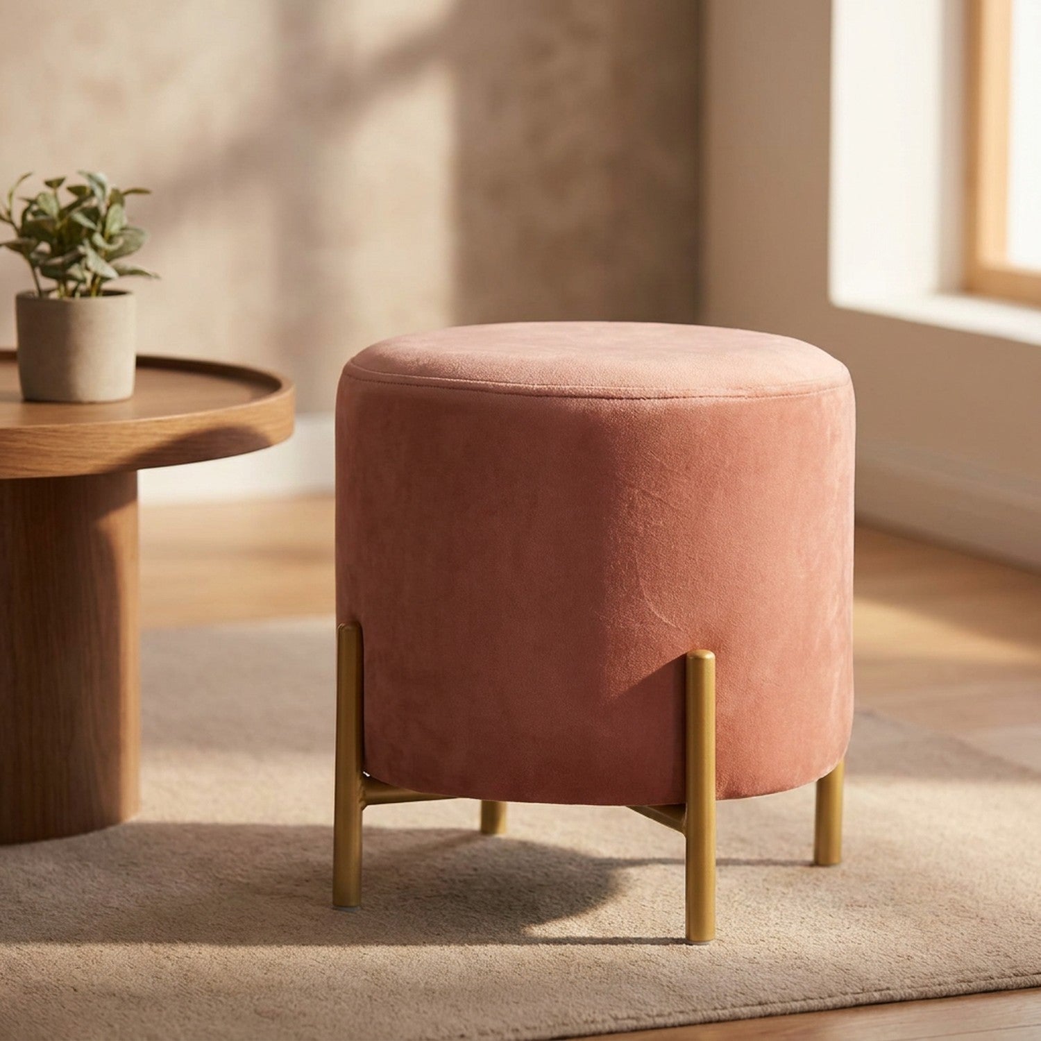 Pouf rond en velours rose avec pieds dorés dans un salon lumineux