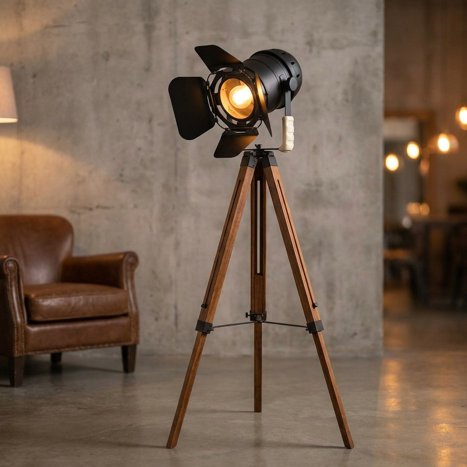 Lampadaire projecteur vintage noir sur trépied en bois dans un salon industriel