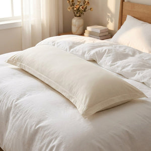 Taie de traversin beige tissu doux posée sur un lit fait dans une chambre chaleureuse