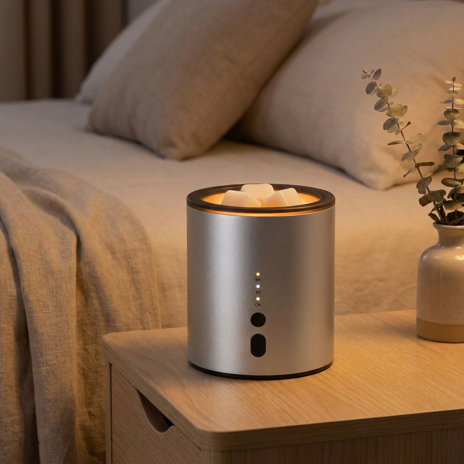 Brûle-parfum électrique en aluminium argenté posé sur une table avec une lumière d'ambiance chaleureuse