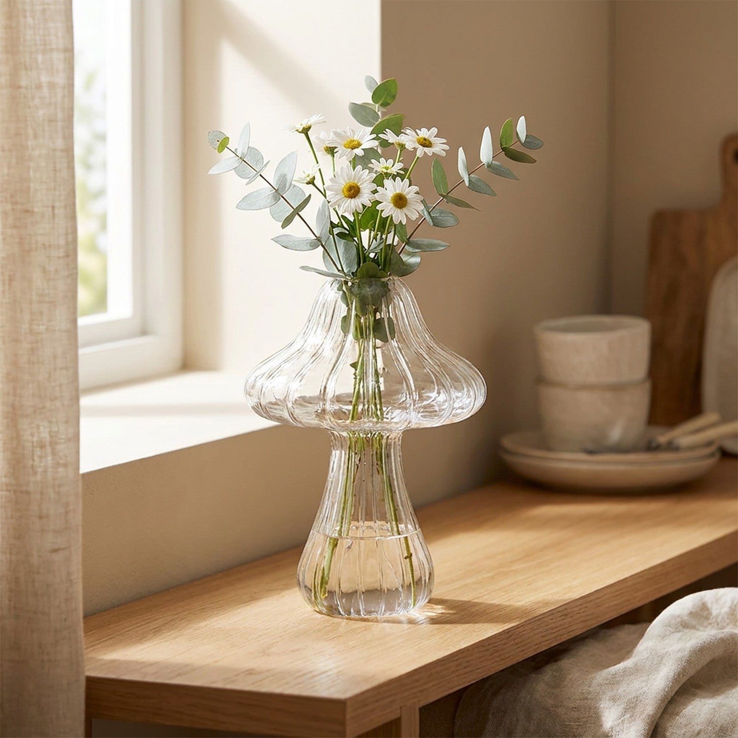 Vase champignon en verre transparent nervuré avec marguerites et eucalyptus sur étagère bois