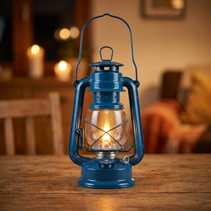 Lanterne à pétrole rétro en métal bleu allumée sur une table en bois dans une ambiance chaleureuse