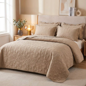 Couvre-lit matelassé beige au motif damassé en relief installé sur un lit avec deux taies assorties dans une chambre chaleureuse