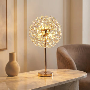 Lampe de table en cristal doré design fleur de soleil allumée sur une console dans un salon moderne