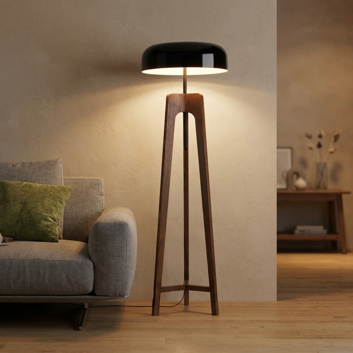 lampadaire trépied en bois au dôme de métal noir allumé dans un salon chaleureux près d'un canapé