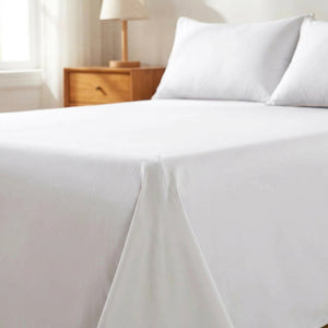 Drap plat en coton blanc posé sur un lit fait dans une chambre lumineuse et chaleureuse
