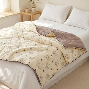 Couette légère à motif petits ours posée sur un lit fait dans une chambre lumineuse