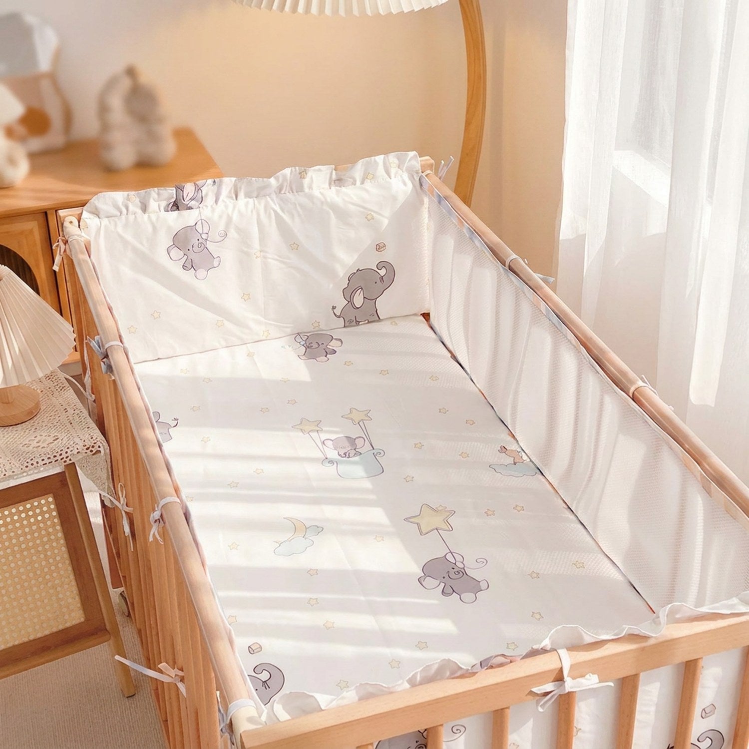 Parure de lit bébé à motif éléphant installée dans un berceau en bois d'une chambre lumineuse