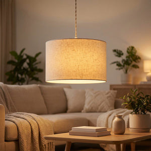 Abat-jour cylindrique en lin beige suspendu en pendentif dans un salon chaleureux