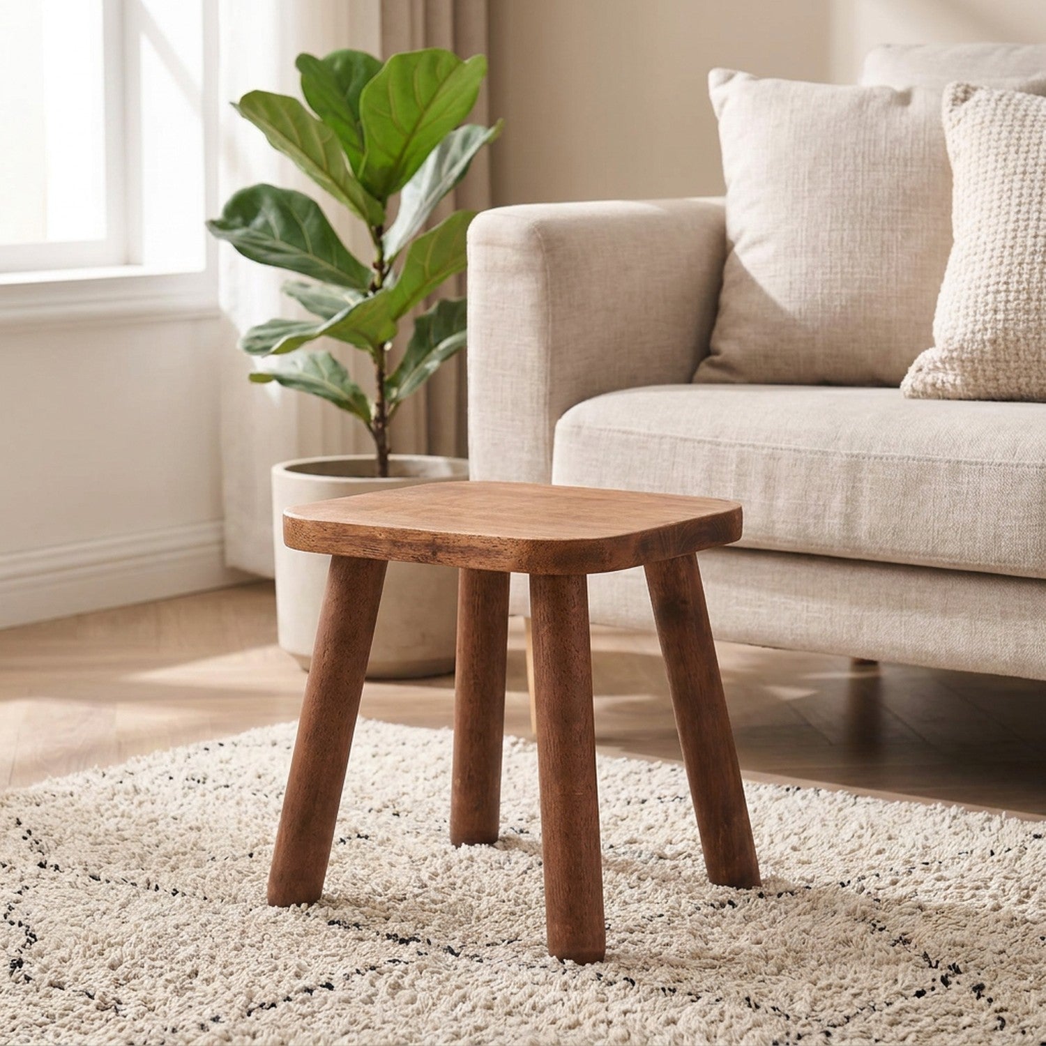 Petit tabouret carré en bois massif noyer posé sur un tapis dans un salon chaleureux