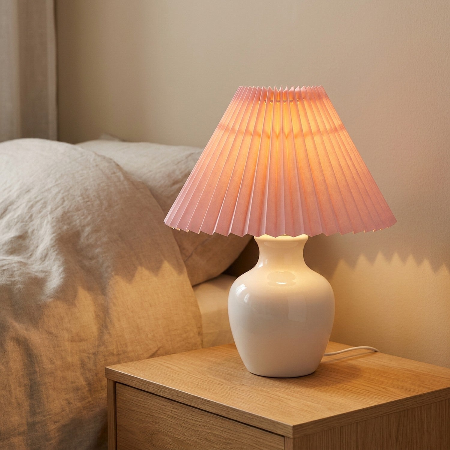 Abat-jour plissé rose style japonais posé sur une lampe de chevet dans une chambre douce