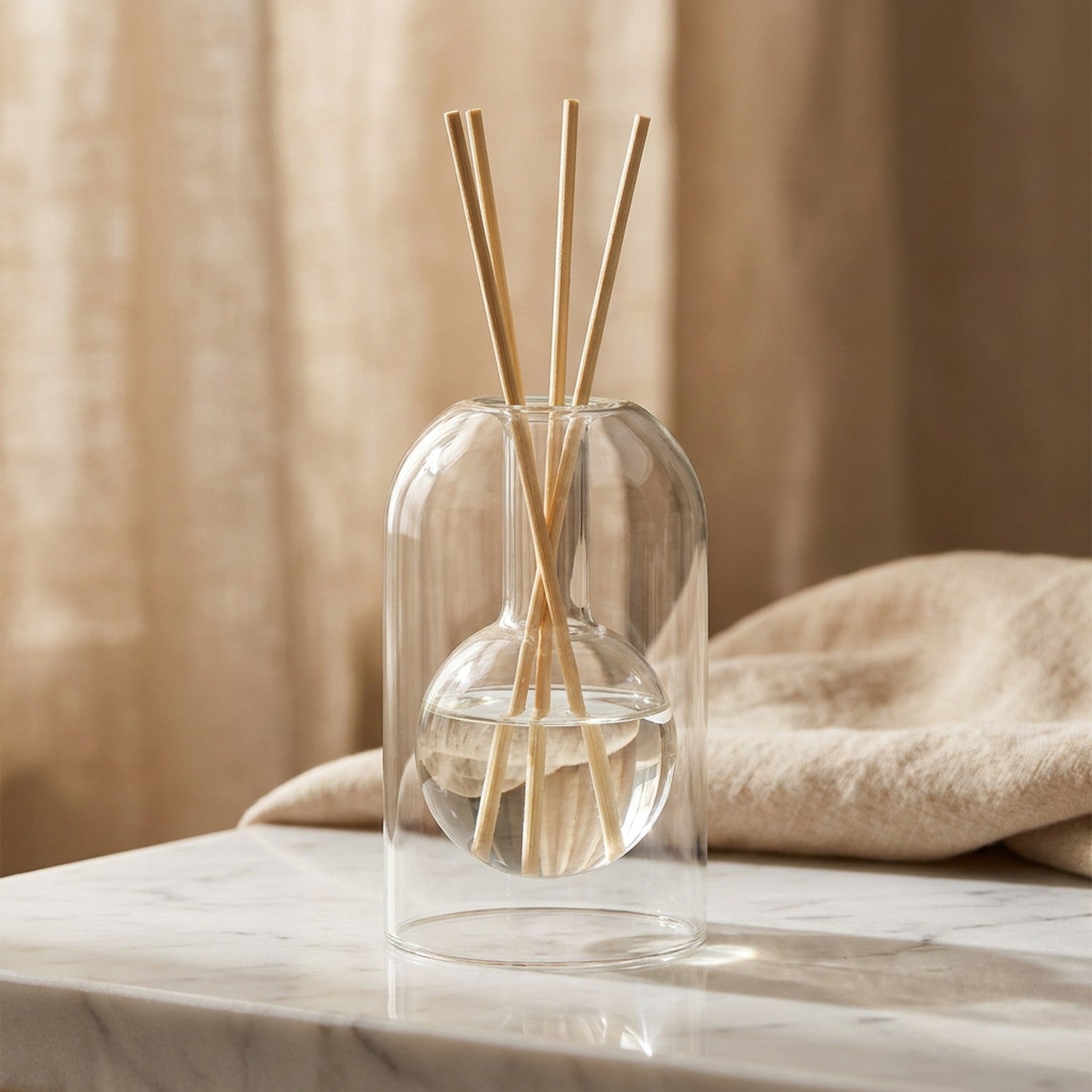 Diffuseur à bâtons en verre double paroi transparent sur surface en marbre fond lin chaud
