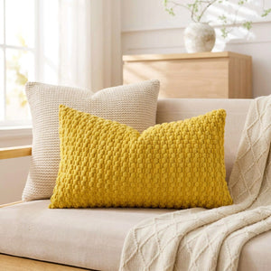 housse de coussin rectangulaire en maille texturée jaune moutarde posée sur un canapé beige lumineux