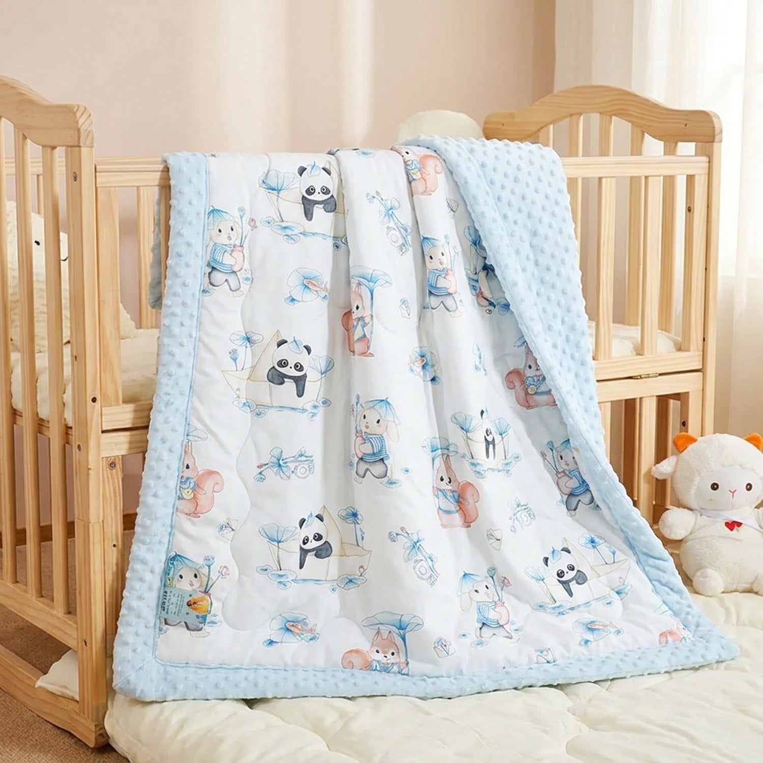Couverture enfant matelassée à motifs de pandas bleus posée sur un lit d'enfant dans une chambre douce