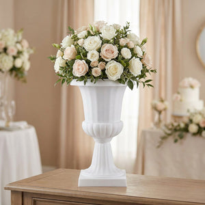 Vase médicis blanc sur colonne haute garni de roses claires dans un intérieur élégant