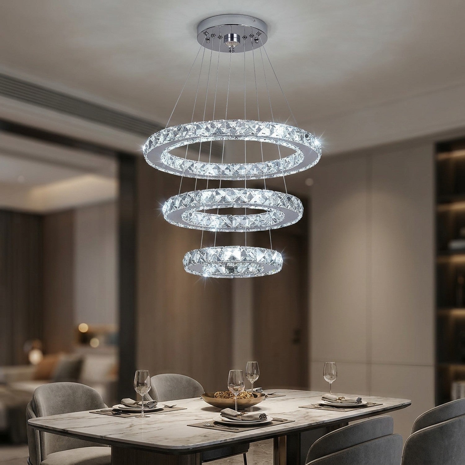 Lustre en cristal argenté à trois anneaux suspendu au-dessus d'une table de salle à manger moderne