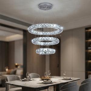 Lustre en cristal argenté à trois anneaux suspendu au-dessus d'une table de salle à manger moderne