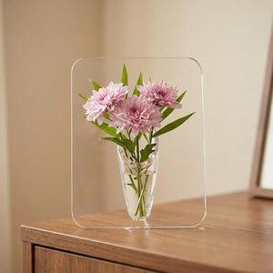 Vase à fleurs en acrylique transparent de forme rectangulaire avec des fleurs roses posé sur une console en bois