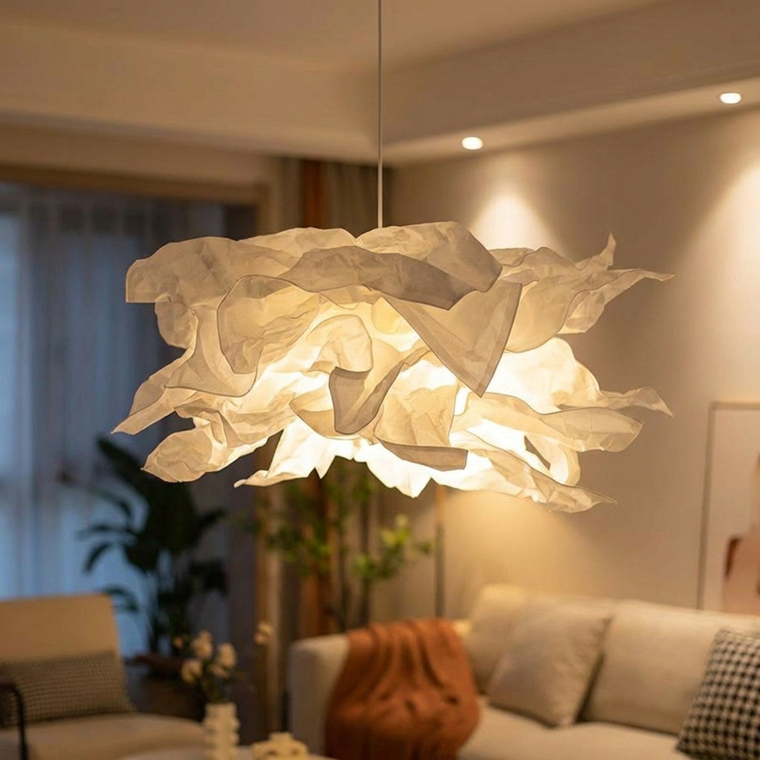 Lustre nuage en papier blanc à fleurs LED allumé suspendu au plafond d'un salon moderne et chaleureux