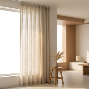 Voilage tamisant aspect lin naturel écru suspendu à une fenêtre dans un salon japandi lumineux