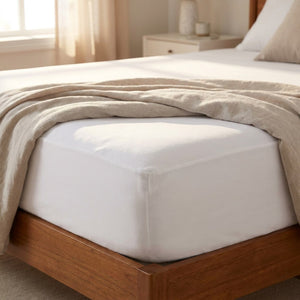 Housse de matelas blanche imperméable ajustée sur un matelas dans une chambre lumineuse