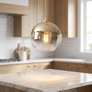 Suspension boule de verre au dégradé doré métallisé avec ampoule Edison allumée dans une cuisine moderne