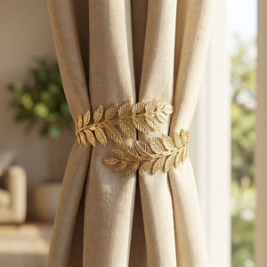 Embrasse de rideau en métal doré à motif de feuilles retenant un rideau beige devant une fenêtre